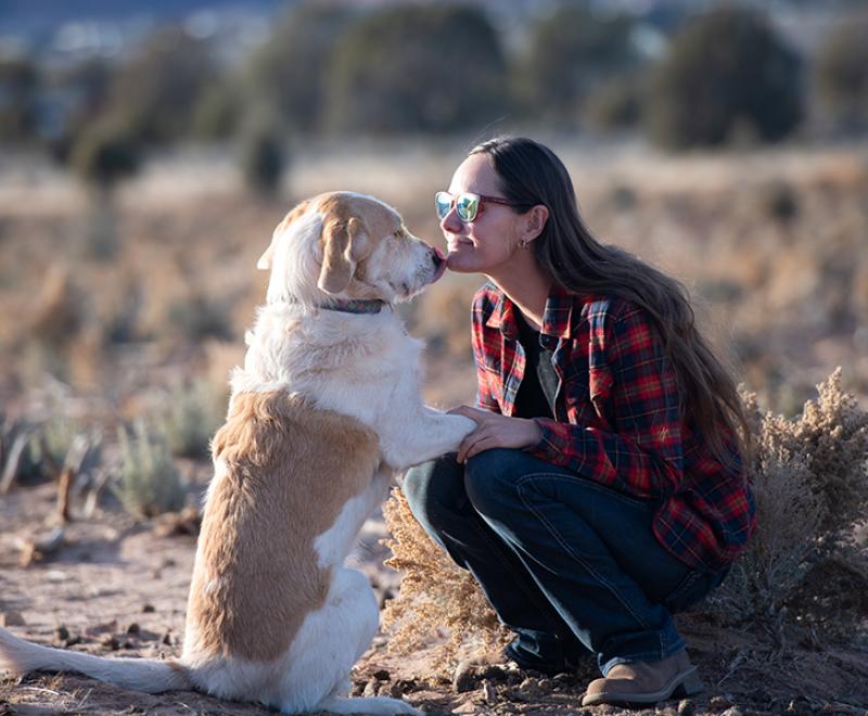 Person kneeling beside a dog whose front paws are up on her knees