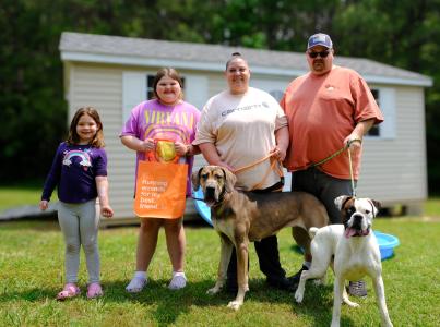 Four people with two leashed dogs in front of a shed
