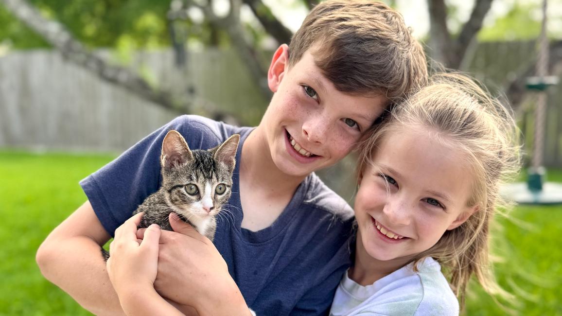 Two children holding Sarah the kitten