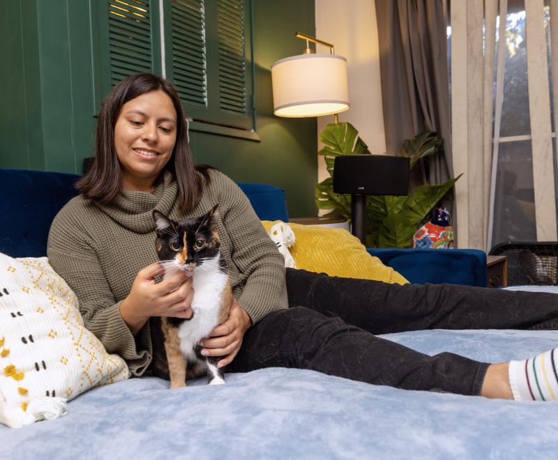 Smiling person relaxing on a bed with a cat