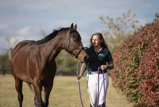 Woman with brown horse in field